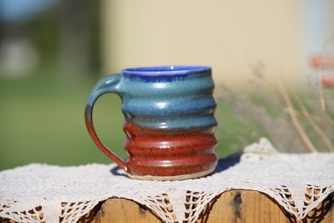 Ribbed stoneware mug in cobalt, teal and rust glaze glowing in golden light