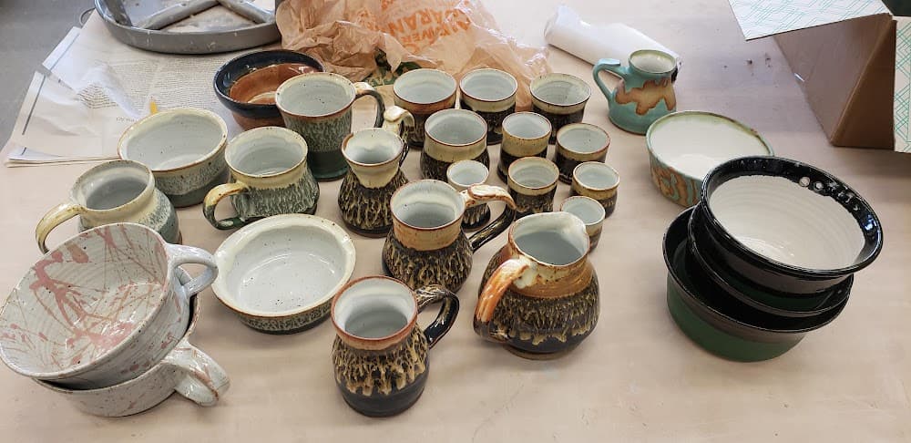 Large kiln unload of mugs and bowls in speckled green, amber, and black glazes