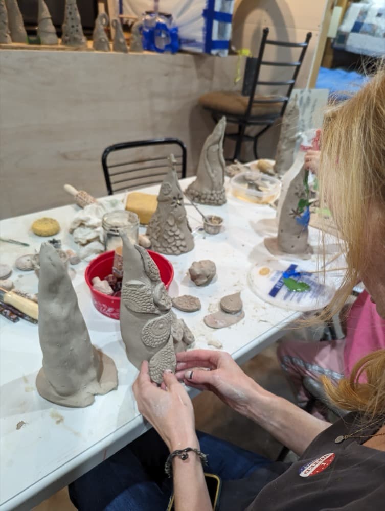 Abby hand-sculpting decorative clay gnomes at her worktable