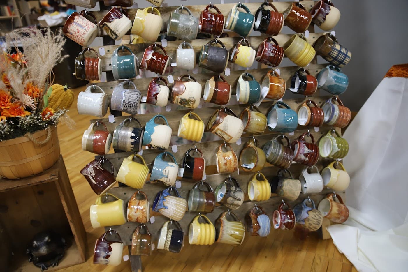 Full mug wall display with dozens of handmade mugs and autumn florals