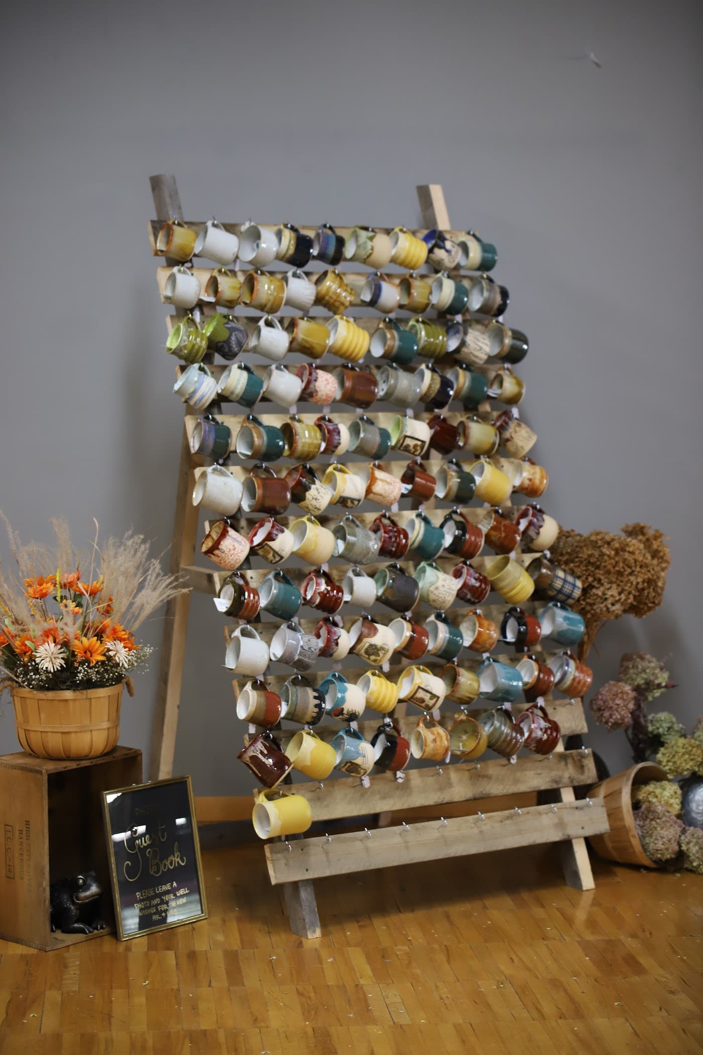 Ladder rack mug wall serving as a wedding guest book with autumn flowers